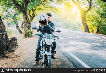 Close-up of motorcyclist man putting on safety helmet. Biker motorcycle putting on safety helmet near of asphalt road. Biker motorcycle safety concept