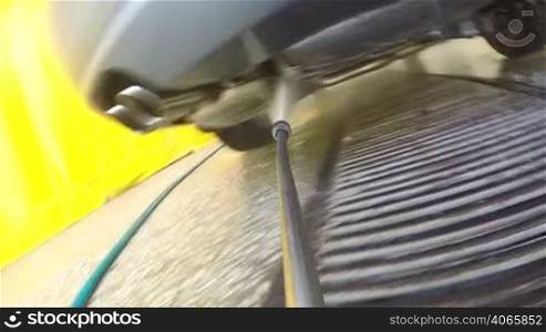 Close-up of nozzle of high pressure washer cleaning car spraying water on vehicle surface in garage or washing service centre