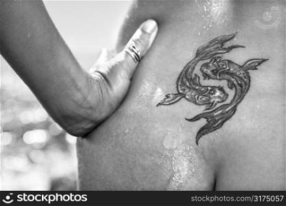 Close up of nude wet Caucasian mid adult womans tattoo of koi fish on lower back.