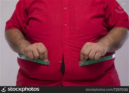 Close up of obese man measuring his overweight stomach with a measurement tape