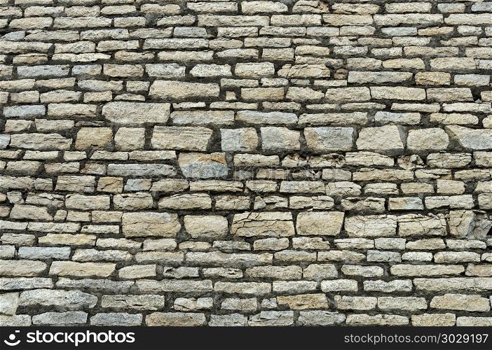 Close up of old rough gray limestone brick wall surface. Rough grey stone brick wall