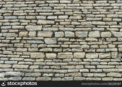 Close up of old rough gray limestone brick wall surface. Rough grey stone brick wall