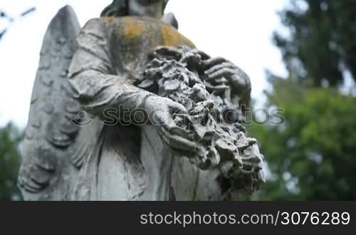 Close up of old statue of angel holding wreath at the cemetery