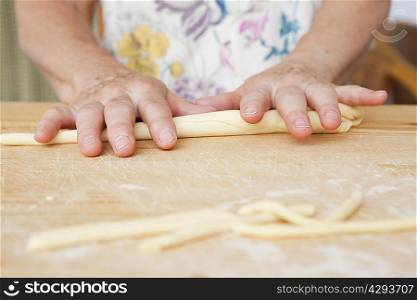 Close up of older woman rolling dough