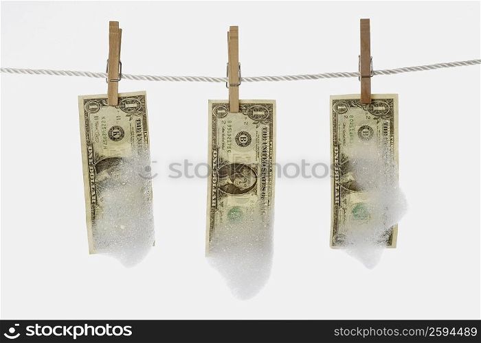Close-up of one dollar bills hanging with clothespins