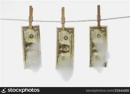 Close-up of one dollar bills hanging with clothespins