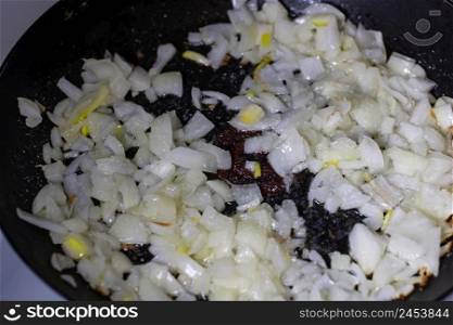 Close up of onion frying in a pan isolated.