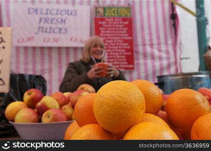 Close-up of oranges on display with senior owner in background
