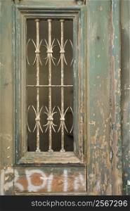 Close-up of ornate door with peeling paint and graffiti in Lisbon, Portugal.