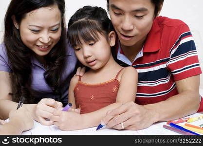 Close-up of parents drawing on paper with their daughter