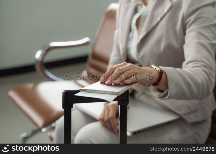 Close up of passport and boarding pass in business woman hand at airport terminal while passenger waiting for boarding time. Traveler concept