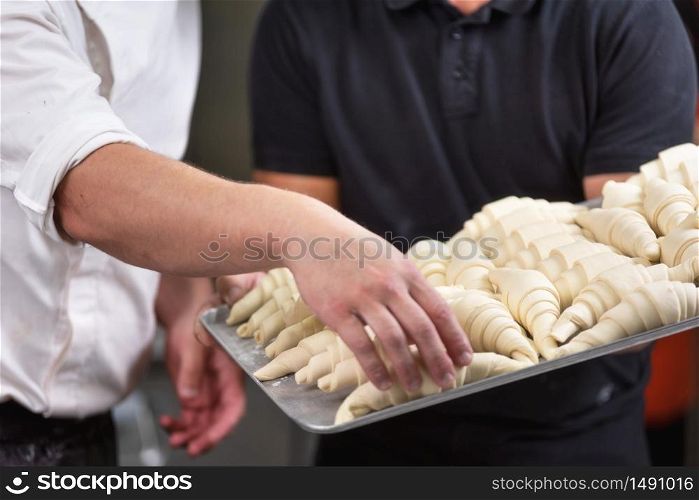 Close up of Pastry Chef showing a tray of fresh raw croissants dough .. Close up of Pastry Chef showing a tray of fresh raw croissants dough.