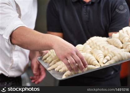 Close up of Pastry Chef showing a tray of fresh raw croissants dough .. Close up of Pastry Chef showing a tray of fresh raw croissants dough.