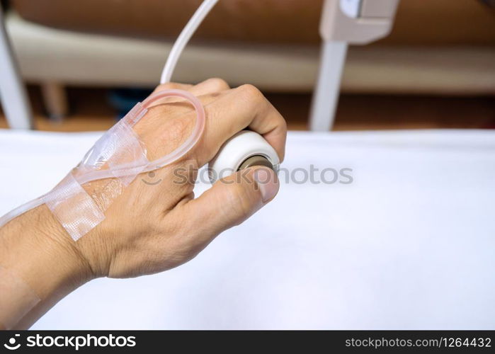 Close-up of patient hand holding and pressing emergency button in hospital room