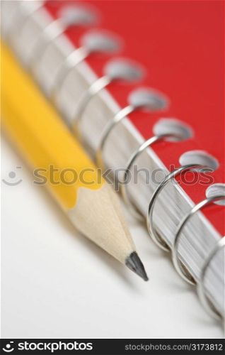 Close up of pencil next to spiral bound notebook.