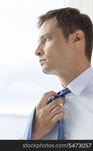 Close-up of pensive businessman loosening necktie in hotel