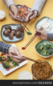 Close up of people using chopsticks with Chinese food