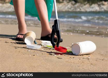 Close Up Of Person Collecting Plastic Waste From Polluted Beach Using Litter Picker