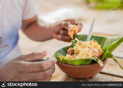 Close-up of person eating vigoron on table. Local person eating a traditional vigoron. The vigoron typical food of Granada, Concept of typical food of Nicaragua