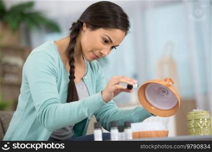 close up of person pouring essential oil for aromatherapy treatment