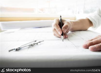 Close-up Of Person's engineer Hand Drawing Plan On Blue Print with architect equipment.