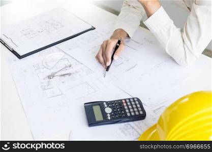 Close-up Of Person’s engineer Hand Drawing Plan On Blue Print with architect equipment, Architects discussing at the table, team work and work flow construction concept.
