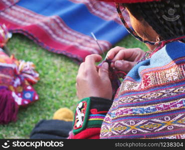 Close up of Peruvian lady in authentic dress spinning yarn by hand. (Peru)