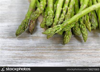 Close up of pile of asparagus; focus on front with shallow depth of field, on rustic white wood