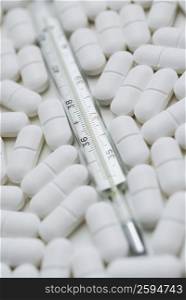 Close-up of pills with a thermometer