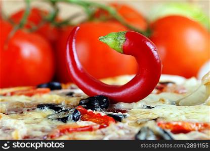 Close up of pizza with tomatoes, cheese, black olives and chili pepper