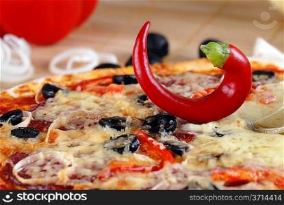 Close up of pizza with tomatoes, cheese, black olives and chili pepper