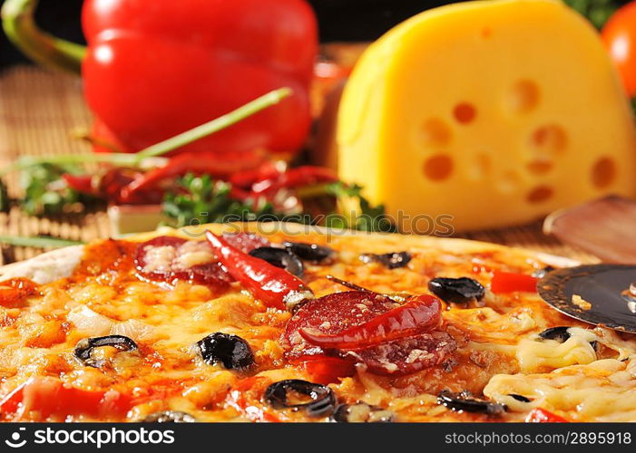 Close up of pizza with tomatoes, cheese, black olives and peppers.