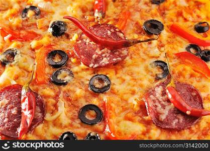 Close up of pizza with tomatoes, cheese, black olives and peppers