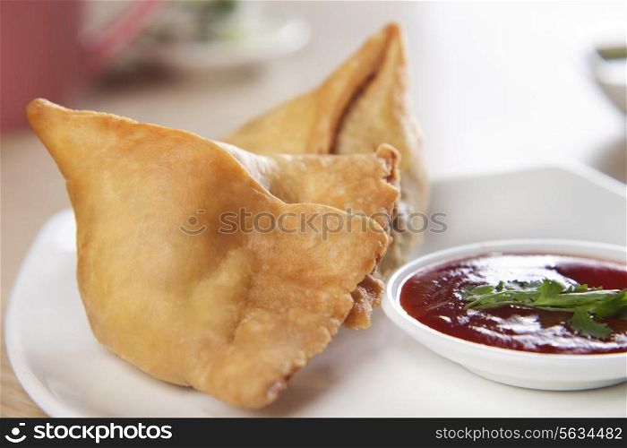 Close-up of plate of samosa with tomato sauce