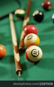 Close-up of pool balls and pool cues on a pool table