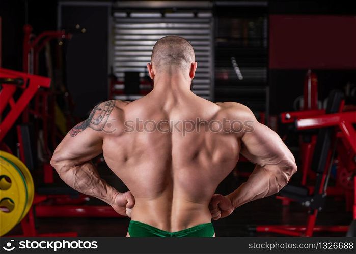 Close up of powerful muscular man posing with muscle contraction at the gym
