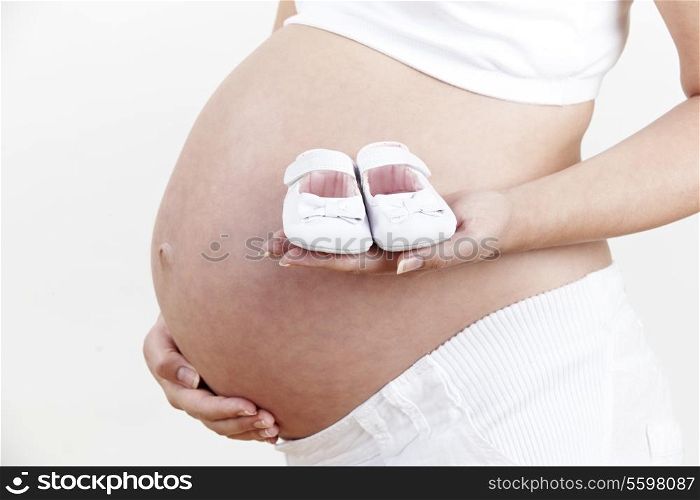 Close Up Of Pregnant Woman Holding Baby Shoes