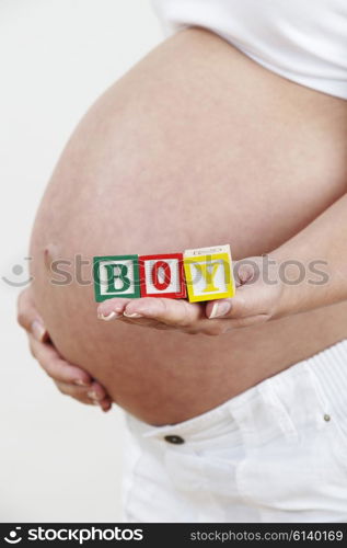 Close Up Of Pregnant Woman Holding Blocks Spelling BOY