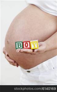 Close Up Of Pregnant Woman Holding Blocks Spelling BOY
