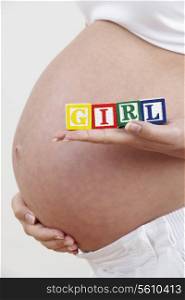 Close Up Of Pregnant Woman Holding Blocks Spelling Girl
