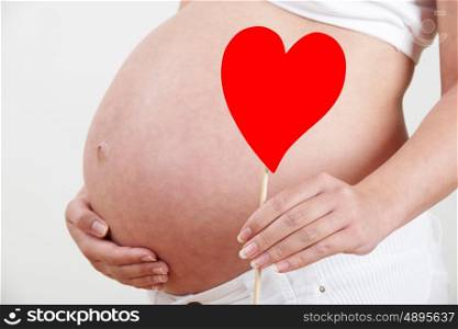 Close Up Of Pregnant Woman Holding Heart Shape On Stick