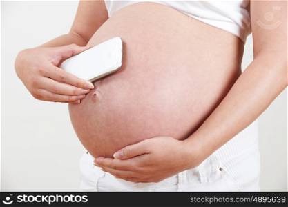 Close Up Of Pregnant Woman Holding Mobile Phone To Bump