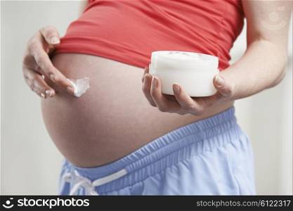 Close Up Of Pregnant Woman Moisturizing Belly