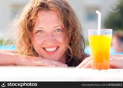 close up of pretty woman in swimming pool with cocktail