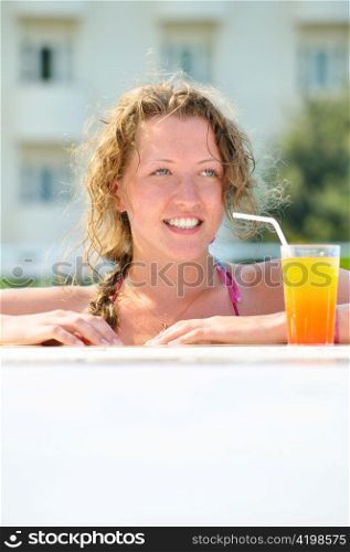 close up of pretty woman looking sideways in swimming pool with cocktail