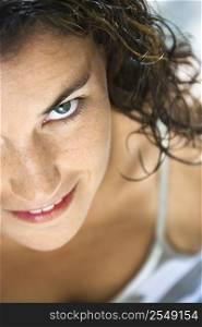 Close up of pretty young adult Caucasian brunette woman looking up at viewer smiling.