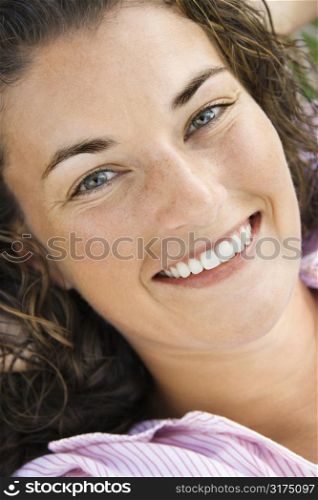 Close up of pretty young adult Caucasian brunette woman smiling at viewer.
