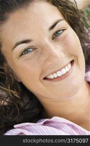 Close up of pretty young adult Caucasian brunette woman smiling at viewer.