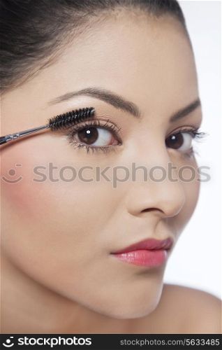 Close-up of pretty young woman applying mascara