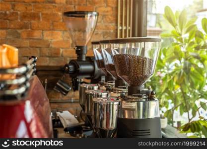 Close up of Professional black electric grinder and Espresso Coffee Machine is on a wooden table in a coffee bar shop in a cafe